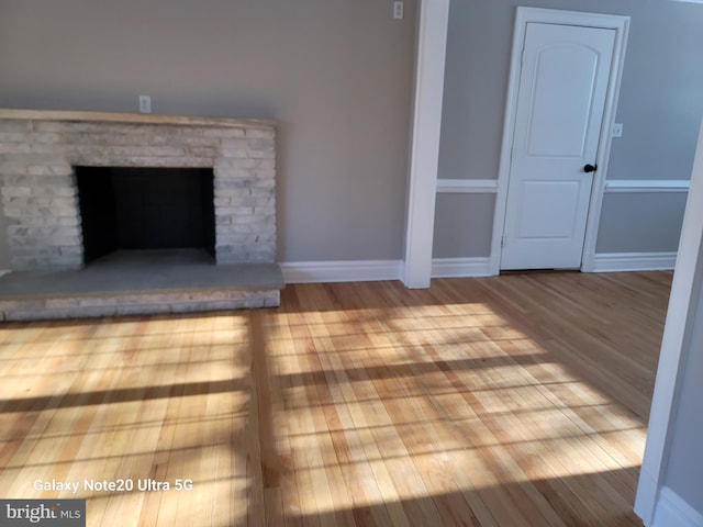 unfurnished living room featuring a brick fireplace and light hardwood / wood-style flooring