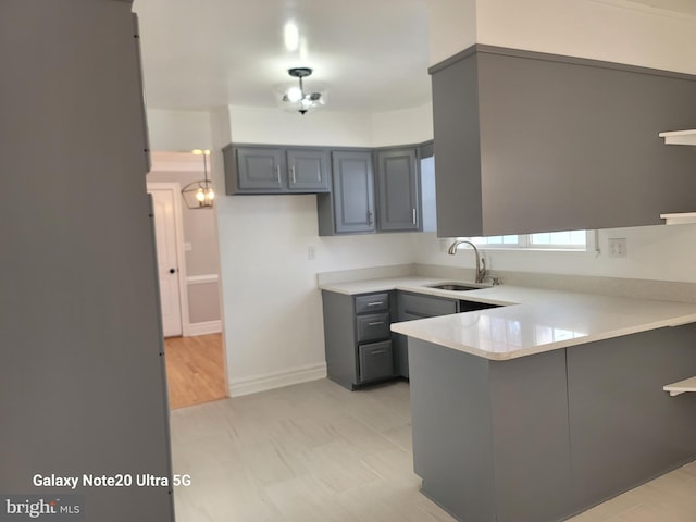 kitchen featuring gray cabinetry, sink, and kitchen peninsula