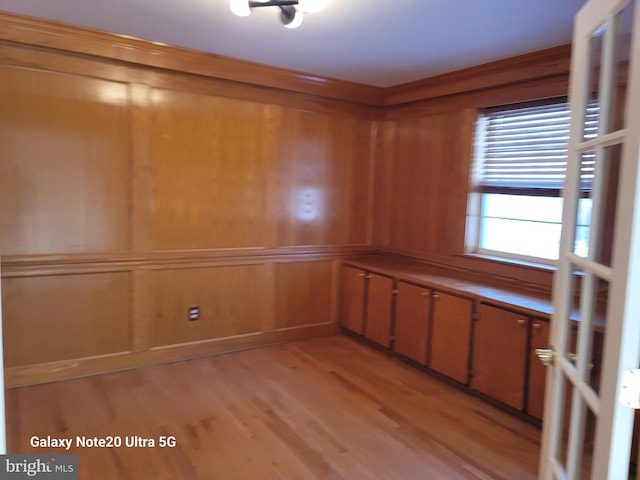 unfurnished room with wood walls and light hardwood / wood-style flooring