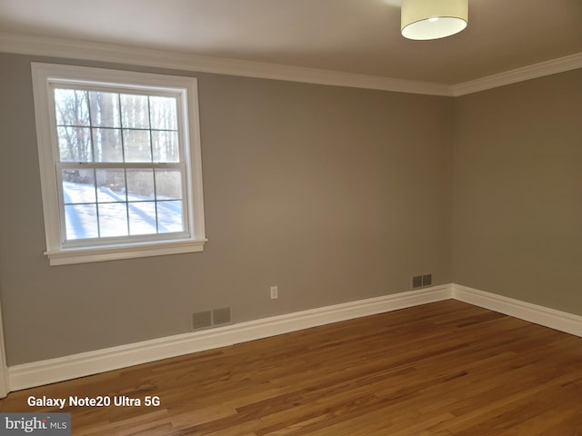 spare room with hardwood / wood-style floors and crown molding