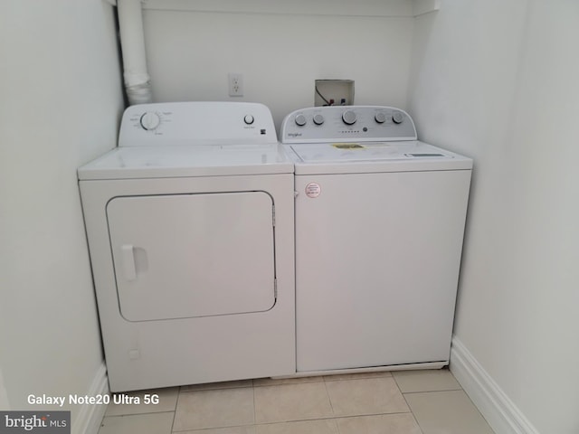 laundry area with separate washer and dryer and light tile patterned floors