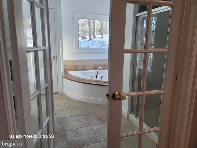 bathroom featuring tile patterned flooring, a bath, and french doors