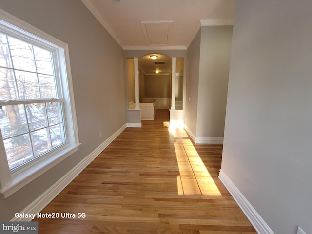 hall with ornate columns, crown molding, and light hardwood / wood-style flooring