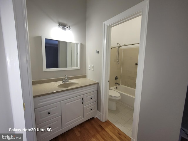 full bathroom with tiled shower / bath combo, vanity, hardwood / wood-style floors, and toilet