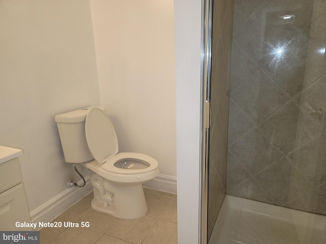 bathroom featuring tiled shower, vanity, toilet, and tile patterned flooring