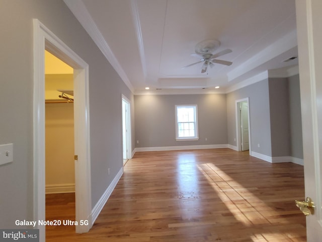 spare room featuring hardwood / wood-style flooring, ceiling fan, crown molding, and a raised ceiling