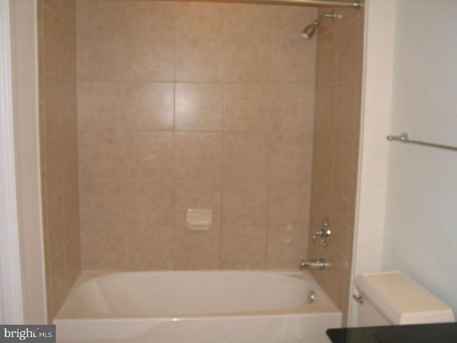 bathroom with tiled shower / bath combo and toilet