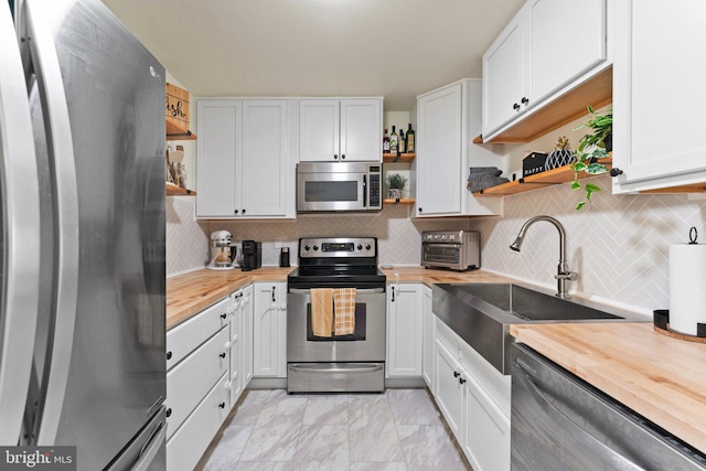 kitchen featuring stainless steel appliances, butcher block counters, and white cabinets