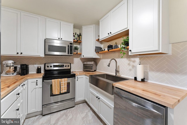 kitchen featuring butcher block countertops, sink, appliances with stainless steel finishes, white cabinets, and decorative backsplash