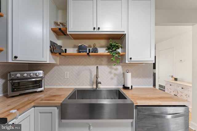 kitchen with wood counters, backsplash, and white cabinets