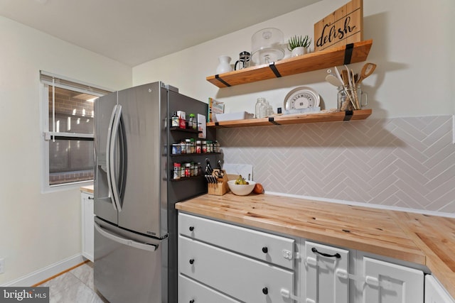 kitchen featuring backsplash, stainless steel fridge, wooden counters, and light tile patterned flooring