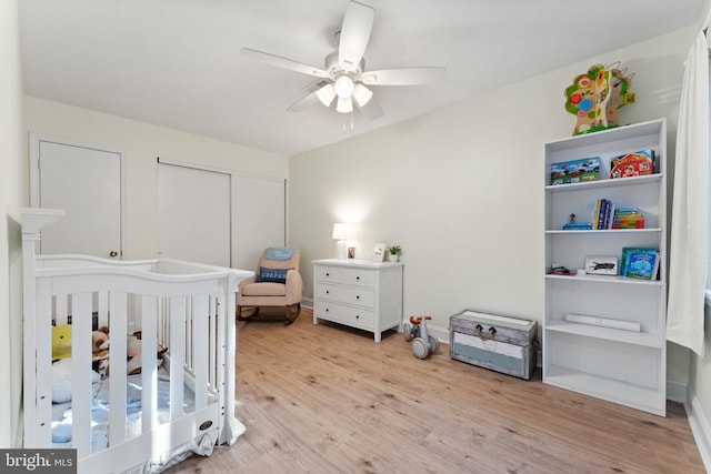 bedroom featuring ceiling fan, light hardwood / wood-style flooring, and a crib