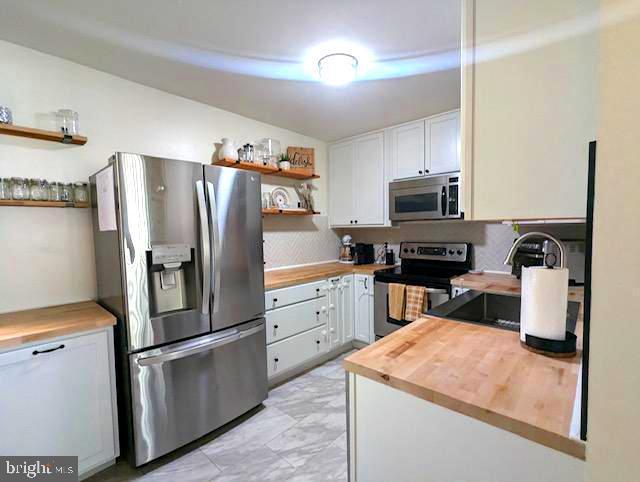 kitchen with white cabinetry, appliances with stainless steel finishes, sink, and wooden counters