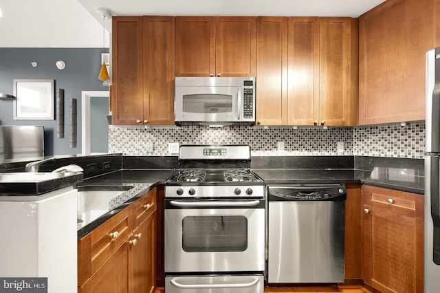 kitchen featuring stainless steel appliances, decorative backsplash, and dark stone counters