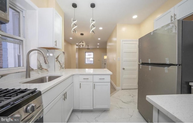 kitchen with white cabinetry, sink, pendant lighting, and stainless steel refrigerator