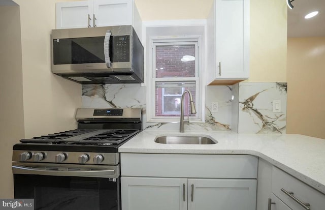 kitchen with white cabinetry, sink, backsplash, and appliances with stainless steel finishes