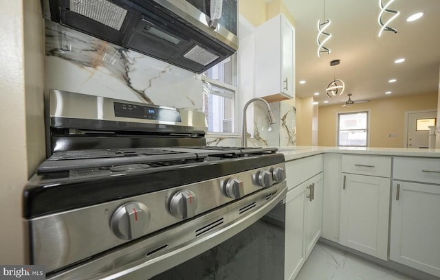 kitchen featuring decorative light fixtures, white cabinets, ceiling fan, stainless steel appliances, and backsplash