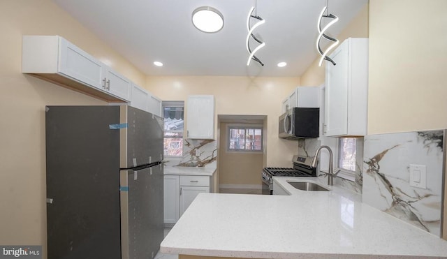 kitchen with appliances with stainless steel finishes, sink, white cabinets, decorative backsplash, and kitchen peninsula