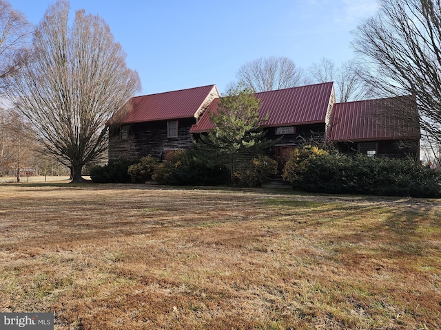 view of property exterior with stone siding, metal roof, and a lawn