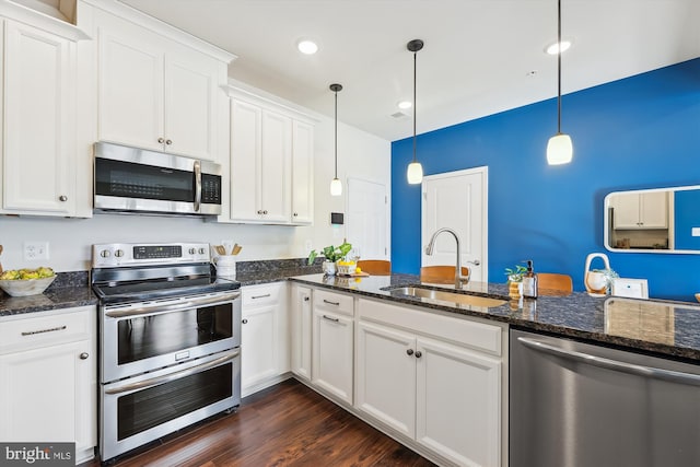 kitchen with pendant lighting, sink, white cabinetry, stainless steel appliances, and dark stone counters