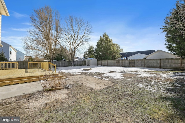 yard layered in snow with a storage shed and a deck