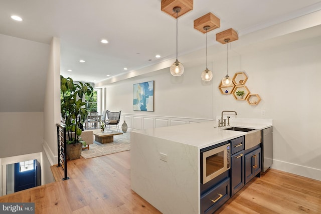 kitchen featuring sink, hanging light fixtures, light hardwood / wood-style flooring, kitchen peninsula, and stainless steel appliances