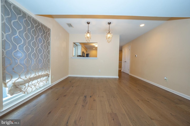 spare room with hardwood / wood-style flooring and a chandelier