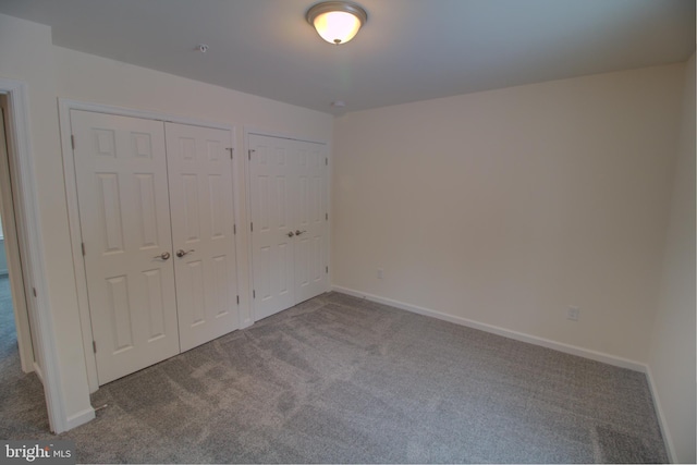 unfurnished bedroom featuring two closets and carpet