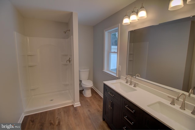 bathroom with walk in shower, vanity, toilet, and hardwood / wood-style floors