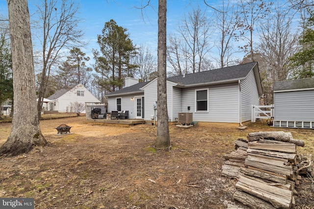 rear view of house with a fire pit, central air condition unit, and a deck