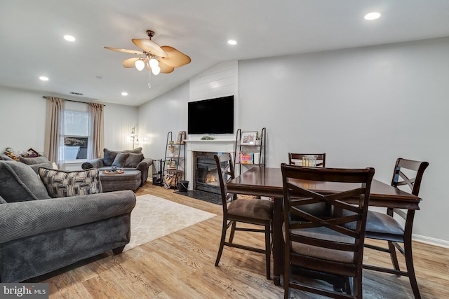 living room featuring ceiling fan, lofted ceiling, and light wood-type flooring