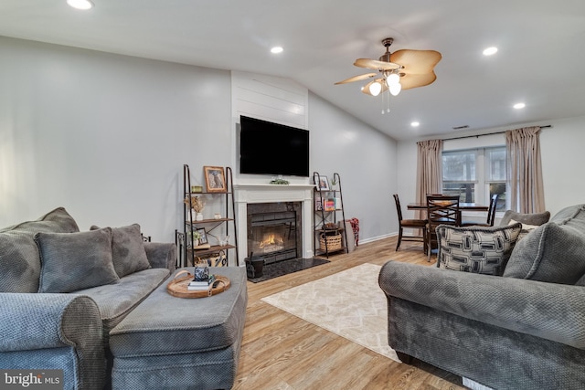 living room featuring ceiling fan, lofted ceiling, and light hardwood / wood-style flooring