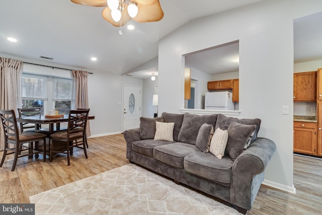 living room with ceiling fan, lofted ceiling, and light wood-type flooring