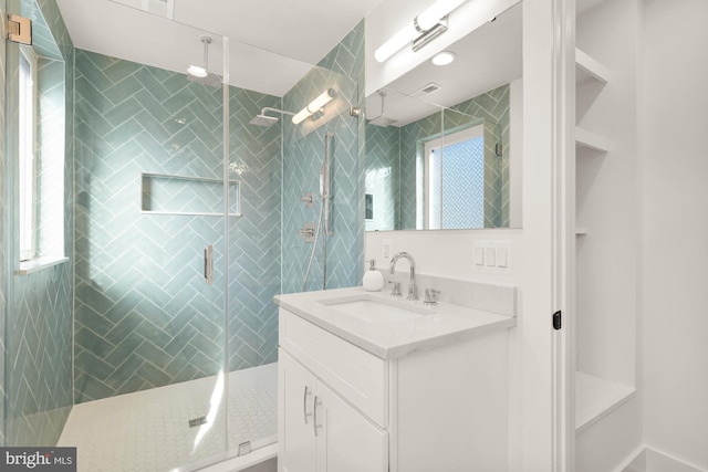 bathroom with a shower with door, vanity, and a wealth of natural light