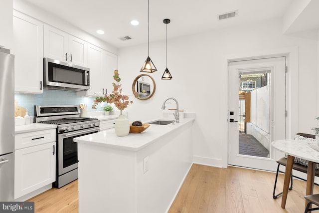 kitchen featuring sink, appliances with stainless steel finishes, pendant lighting, decorative backsplash, and white cabinets