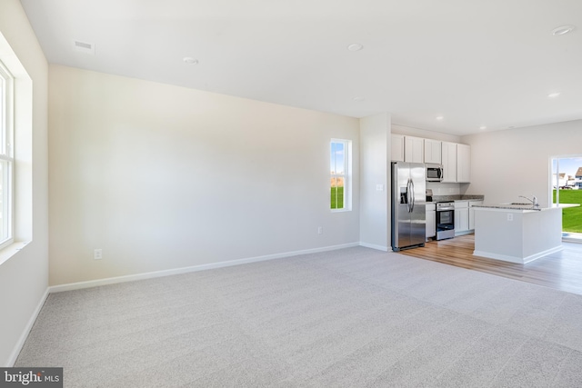 unfurnished living room with light carpet and sink