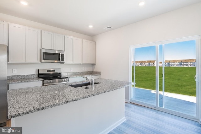 kitchen featuring light stone countertops, appliances with stainless steel finishes, sink, and white cabinets