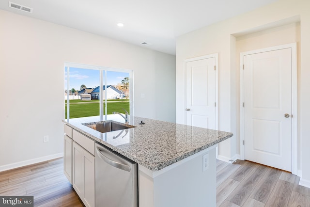 kitchen featuring white cabinetry, sink, stainless steel dishwasher, light stone counters, and a center island with sink