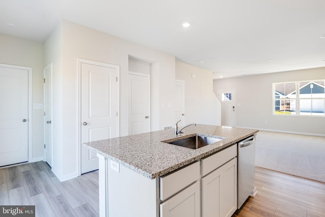 kitchen featuring white cabinetry, dishwasher, sink, an island with sink, and light stone counters