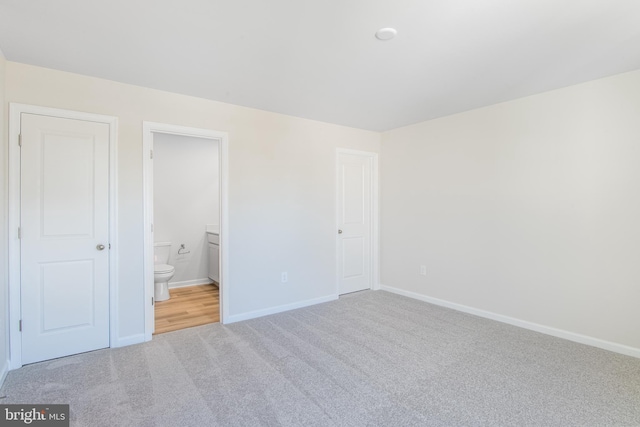 unfurnished bedroom with light colored carpet and ensuite bath