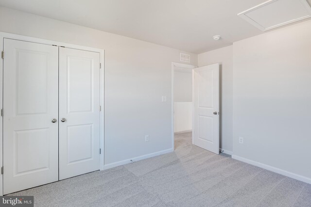 unfurnished bedroom with light colored carpet and a closet