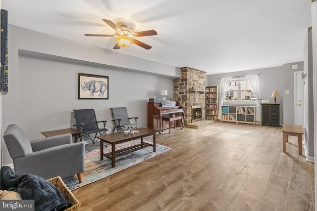 living room with ceiling fan, a fireplace, and light hardwood / wood-style floors