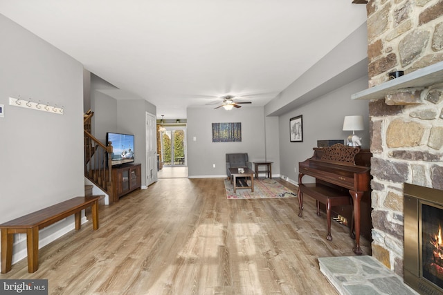 living room featuring ceiling fan, a fireplace, and light hardwood / wood-style floors