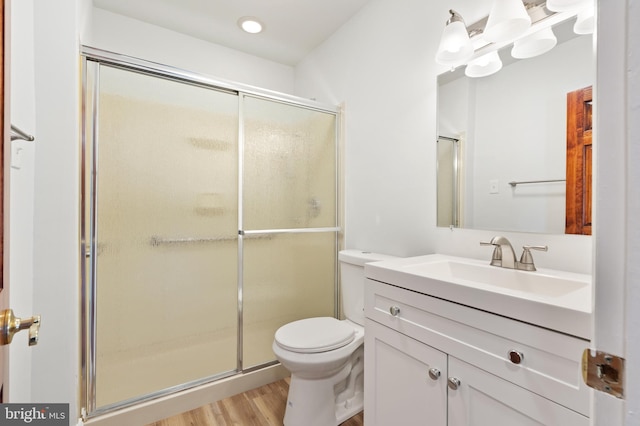 bathroom featuring a shower with door, wood-type flooring, vanity, and toilet