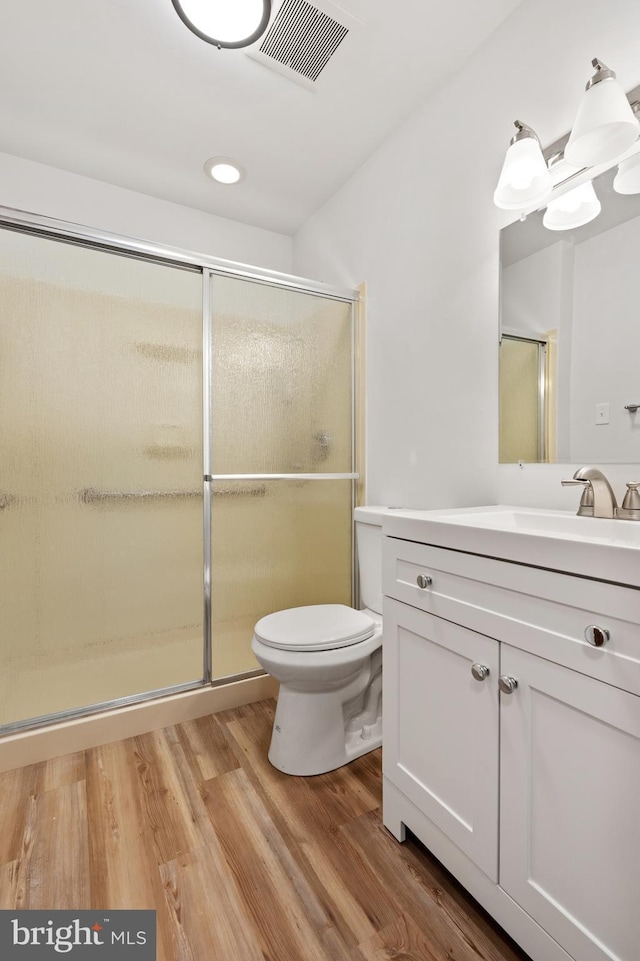 bathroom featuring vanity, hardwood / wood-style floors, toilet, and walk in shower