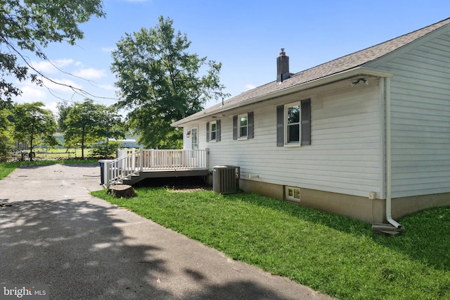 view of property exterior with central AC unit, a deck, and a lawn