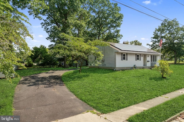 view of front of home with a front yard and solar panels