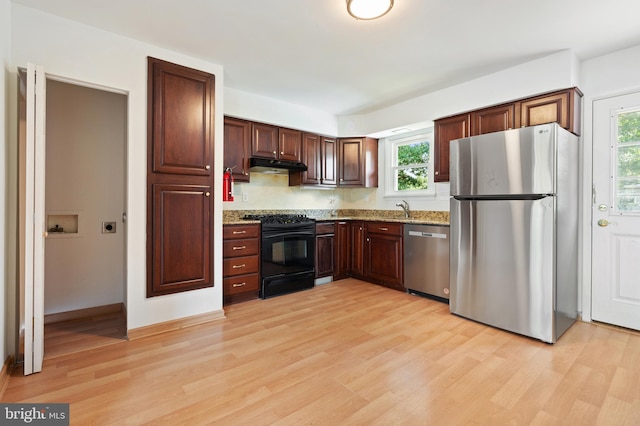 kitchen featuring sink, light hardwood / wood-style flooring, light stone countertops, and appliances with stainless steel finishes