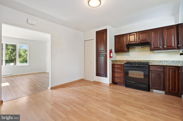 kitchen with black range oven, light stone counters, light hardwood / wood-style flooring, and dark brown cabinetry