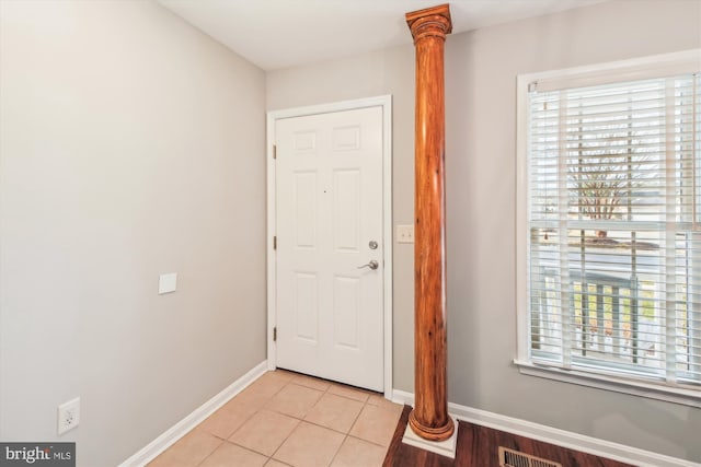 entryway featuring ornate columns, a wealth of natural light, and light tile patterned floors